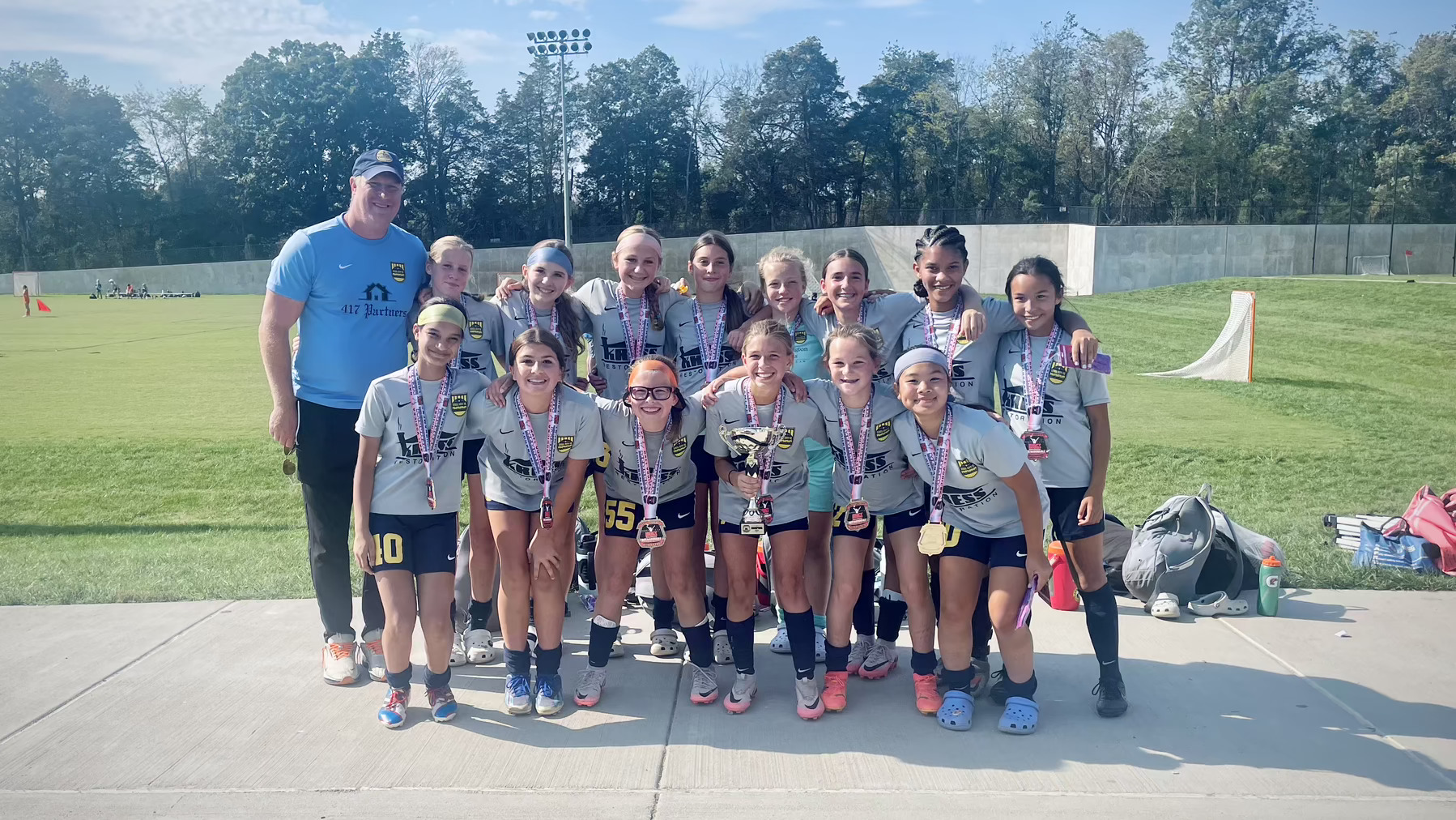 A girls soccer team posing with their championship medals and trophy.